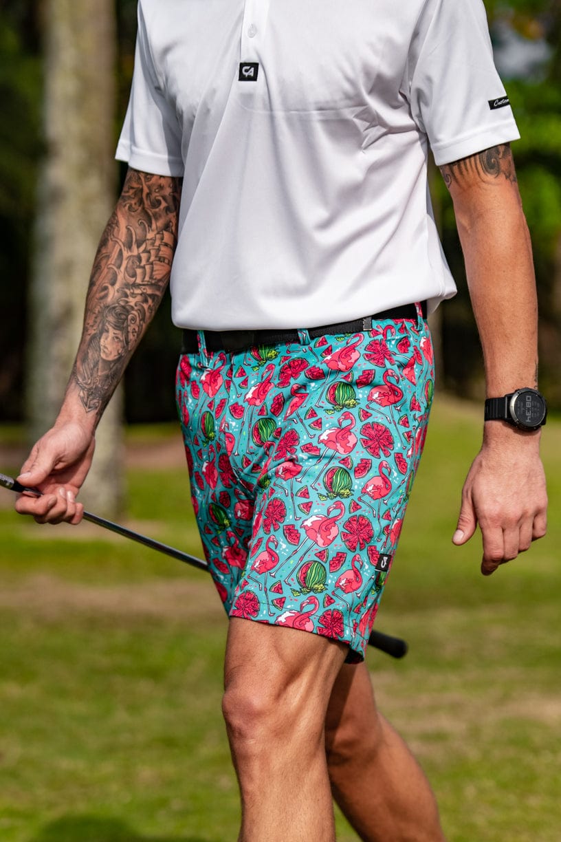 Turquoise floral golf shorts with a black belt and white polo shirt.